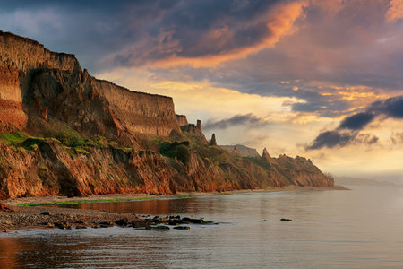 Colorful sunset at the sea coast. Clay rocks and sand dunes in the wild seasideの写真素材