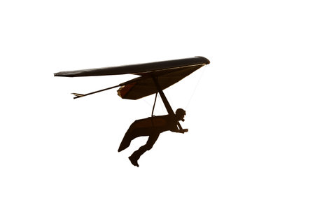Real hang glider wing silhouette isolated in white. Pilot with his legs out of harness