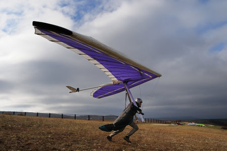 Hang glider pilot runs fast on a slope before being airborne. Extreme sportの写真素材