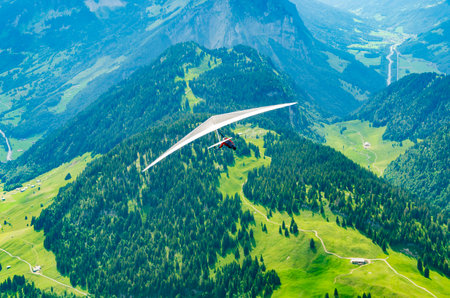 Brave hang glider pilot soar in the mountains in Austrian Alps in Diedams. Extreme sports in European Alpsの写真素材