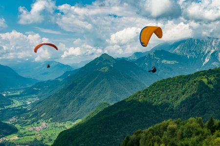 Colorful paraglider wings fly in the mountains near Tolmin, Slovenia. Soca valley, the Europe popular tourist destination, Mecca for extreme sports and active lifestyle.のeditorial素材