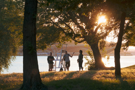 2023-07-09 Kyiv, Ukraine. Friends meeting in the park on the riverside. Sunset on the Dnipro river, Ukraine.のeditorial素材