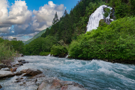 Fast flow of alpine river and beautiful waterfall in the mountain valley. Scenic nature of Austriaの写真素材