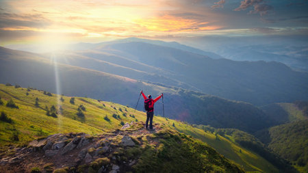 Happy hiker girl on the mountain top enjoys the view with stretched armsの写真素材