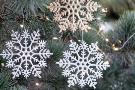 Artificial snowflakes decoration on the Christmas tree. Close up of natureal Christmas tree with decorations and garlands.の写真素材