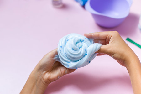 The child is playing with a blue slime toy with small blue balls. Blue slime toy with blue balls on...