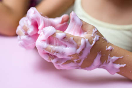 The child plays with a pink slime toy on a pink background.の写真素材