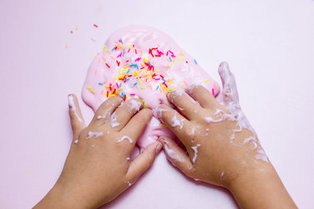 Pink slime toy with colorful neon sticks. Pink toy slime on a pink background.