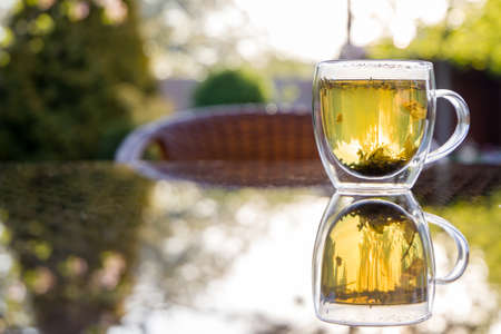 Cup with herbal tea on the table, gazebo in the backyardの写真素材