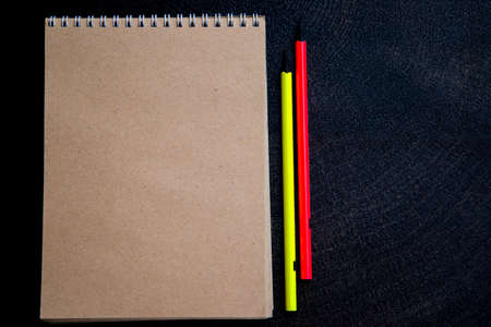 notebook with yellow and orange pencils on a dark backgroundの写真素材