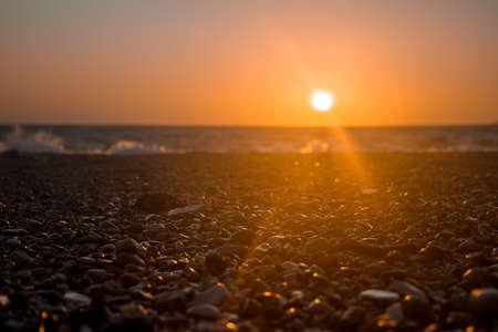 Sunset at sea in summer, pebble beach.の写真素材