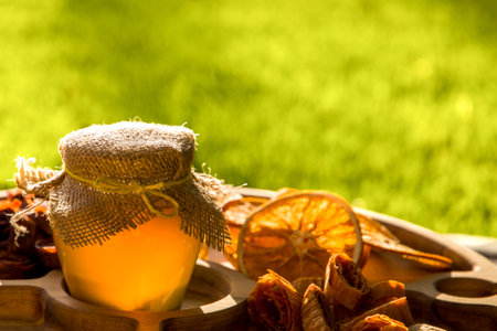 Still life with a jar of honey and dried fruits on a background of green grass.の写真素材