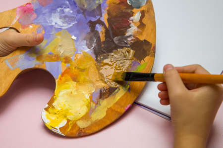 The child draws with a brush on a palette holding it.の写真素材