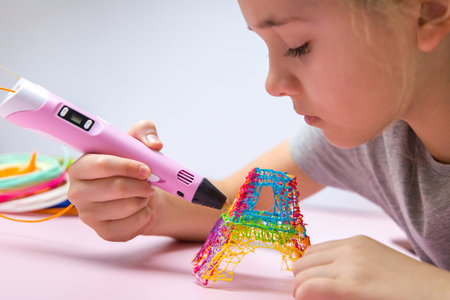 The girl in a gray T-shirt makes a 3d pen colorful tower.