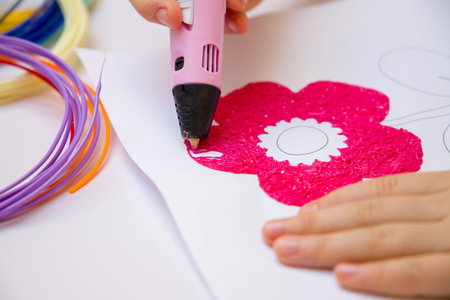 A girl with a 3D pen draws a pink flower. close-up view.