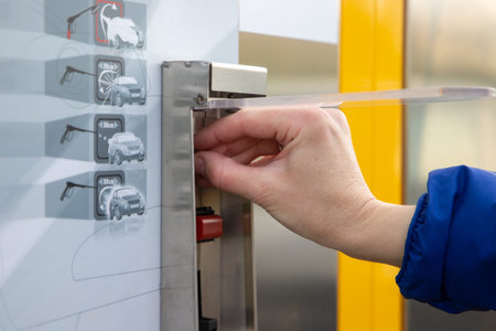 Woman inserting coin money in car washing machine.