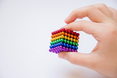 A child's hand holds a cube made of colorful round magnetsの写真素材