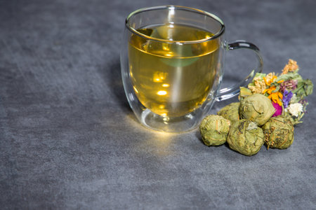 Cup of green tea with dried flowers on a gray background.の写真素材
