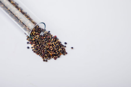 Black quinoa seeds in a glass test tube, close-up, selective focus.