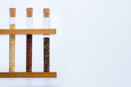 Glass tubes with red, white and black quinoa seeds on a white background.の写真素材