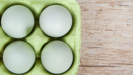 blue eggs in a green cardboard on the wooden background, close-up, top vievの写真素材
