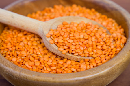 red lentils in wooden spoon on a brown backgroundの写真素材