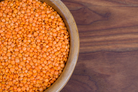 Red lentils in a wooden bowl on a wooden table.uの写真素材