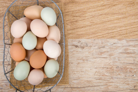 Top view of fresh chicken eggs in metal basket on wooden background.の写真素材