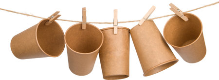 Brown paper cups hang on a natural linen thread, attached with wooden clothespins. isolated on white.の写真素材