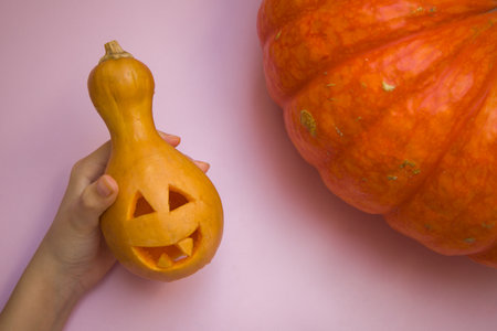 Halloween pumpkin in hand on a pink background. The concept of Halloween.の写真素材