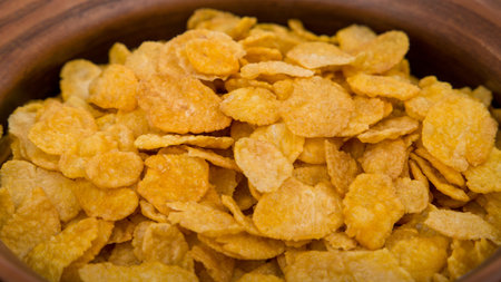 Cornflakes in a wooden bowl. Close-up image.