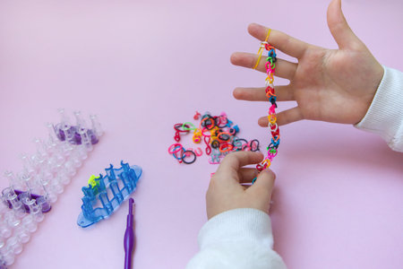 a little girl is making a toy with colored mini rubber bandsの写真素材