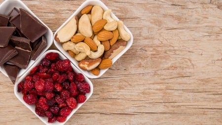 Mix of nuts, dried cranberry, chocolate and almonds over wooden backgroundの写真素材