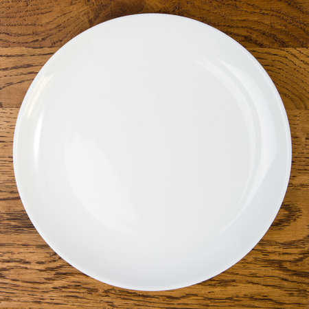 Empty white plate on wooden table. Top view with copy space.の写真素材