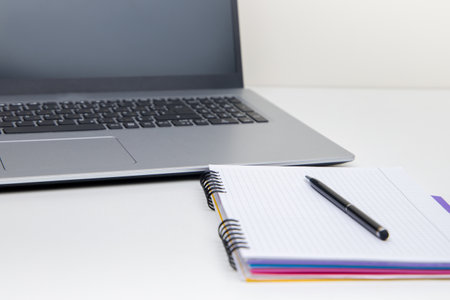 Laptop with notepad and pen on white desk, stock photoの写真素材