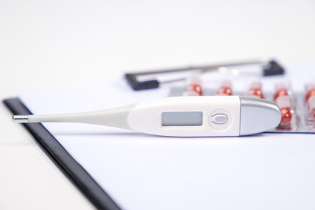 Electronic thermometer and pills on white background. Medical equipment.の写真素材