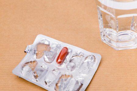 Pills in blister pack and glass of water on brown background.の写真素材