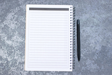 Blank notepad with pen on concrete background. View from above