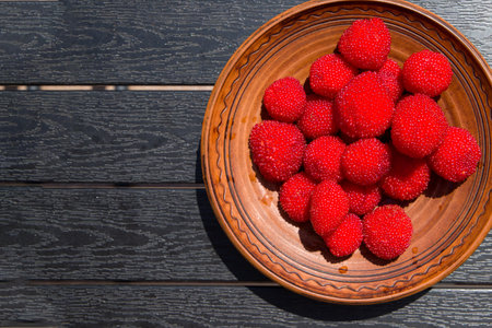 Red balloon berry or strawberry raspberry in a clay bowl. Top view.の写真素材