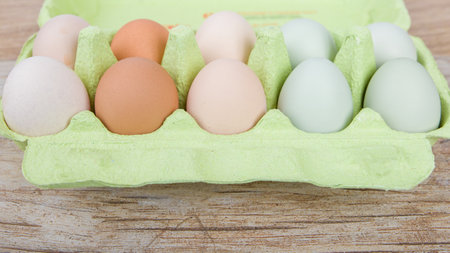 Eggs in a green cardton on a wooden background.の写真素材