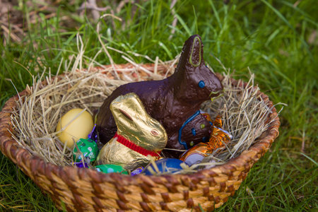 Easter chocolate bunny and eggs in a wicker basket on green grass
