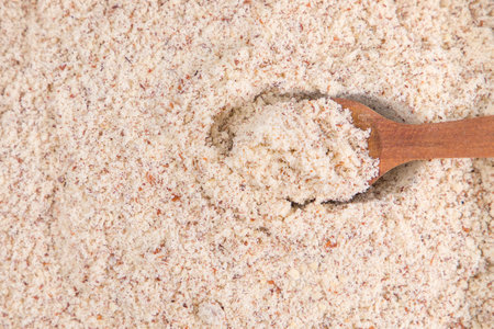 Heap of almond flour with wooden spoon, close up. Top view.の写真素材