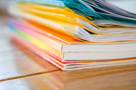 Stack of colorful magazines on wood table. Selective focus with shallow depth of field