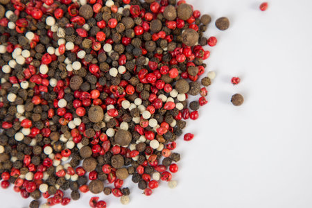 pink and black peppercorns on a white background close upの写真素材