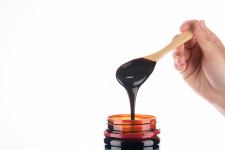 Grape molasses flowing from the spoon on wooden background