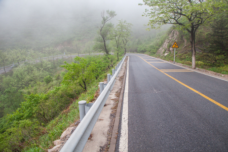 The rugged mountain road is shrouded in haze in Beijing, Chinaの写真素材