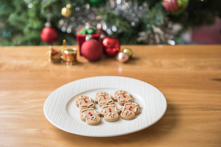 a plate of gingerbread man onthe wooden table and Christmas decorationsの写真素材