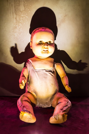 A scary old, broken doll against a damaged wall.の写真素材