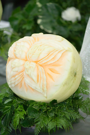 Cantaloupe carving in the form of flower, fern leaves on table set.の写真素材