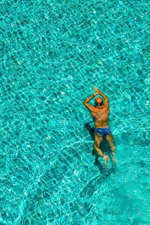 Man swimming in the crystal-clear pool.の写真素材
